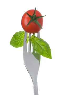 Tomato and basil on a fork on white Stock Photos
