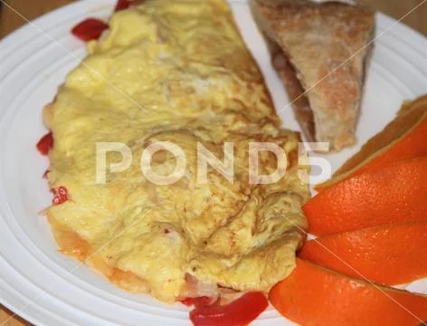 Tomato and cheese omelet with apple turnover and orange wedges Stock Photos