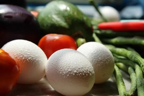 Tomato and eggs display with selective focus and fresh various raw organic veget Stock Photos