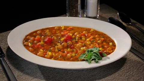 Tomato bean soup or stew on table with camera pan and sprinkling peppers Stock Footage 102137639