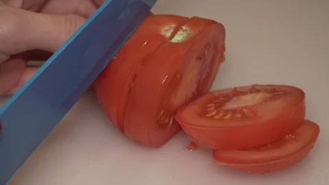 Tomato being cut with a knife by a woman's hand Stock Footage 84238434