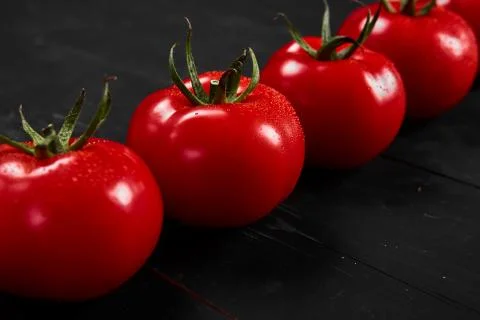 Tomato on a black background with realistic reflection and water drops. Fresh Stock Photos