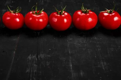 Tomato on a black background with realistic reflection and water drops. Fresh Stock Photos