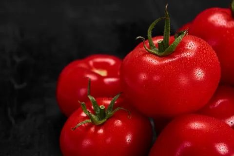 Tomato on a black background with realistic reflection and water drops. Fresh Stock Photos