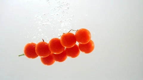 Tomato cherry falls into the water with bubbles. Stock Footage 90025978