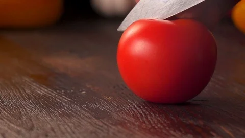 Tomato cutting closeup. Kitchen knife cutting fresh tomato on wooden cutting Stock Footage 120305194