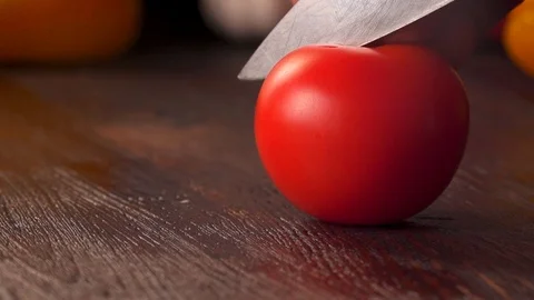 Tomato cutting closeup. Kitchen knife cutting fresh tomato on wooden cutting Stock Footage 120305560