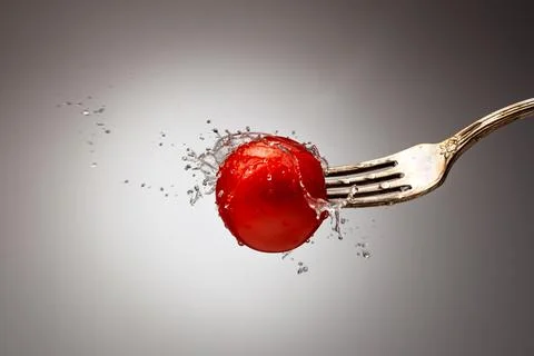 Tomato on a fork in splashes of water on a gradient background Stock Photos