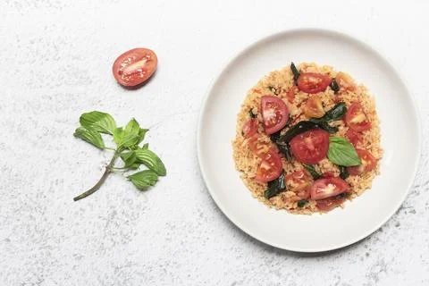 Tomato fried rice has basil in bowl on white slate table Stock Photos