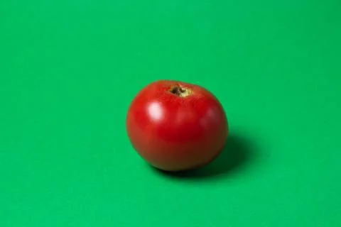 Tomato on a green background.  Stock Photos