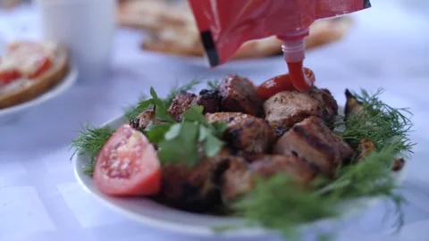 Tomato ketchup being squeezed onto grilled barbecue meat dish. Video stock 313815328