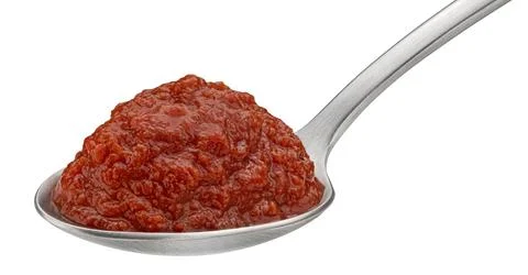Tomato paste in spoon isolated on white background Stock-Fotos