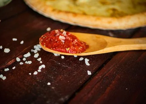 Tomato paste in a wooden spoon on the table Stock Photos