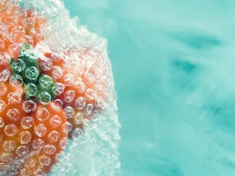 Tomato in plastic package on turquoise Stock Photos