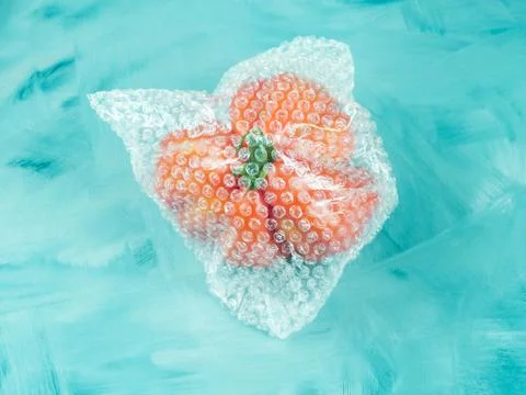 Tomato in plastic package on turquoise Stock Photos