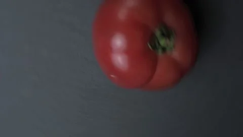 The tomato rotates rapidly on the black slate surface. Stock Footage 130633436