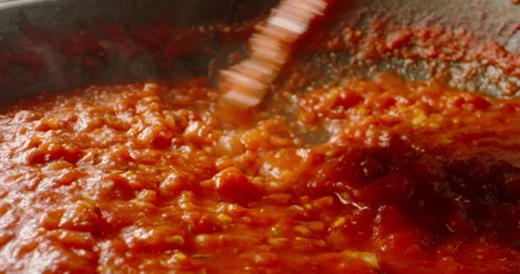 Tomato sauce boiling in a pan, being stirred with a spoon. Hot tomato sauce Stock Footage 154874593