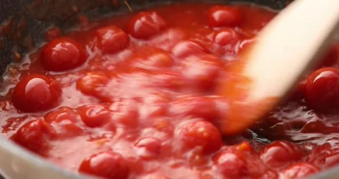 Tomato sauce boiling in a pan with bubbles and steam, stirring with a spoon. Stock Footage 249663274