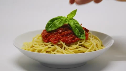 Tomato sauce pasta with fresh basil. Hand puts basil on the top. Stock Footage 164873304
