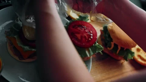 Tomato slice placed onto an open cheeseburger, 4K Stock Footage 341117713