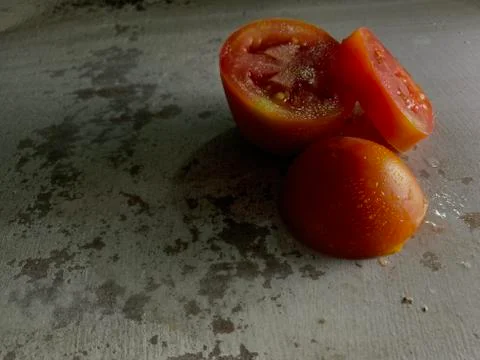 Tomato sliced with drops of water on rustic background in studio. Vegetable P Stock Photos