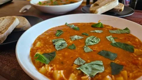 Tomato soup with basil, ciabatta bread, and fresh ingredients Stock Photos