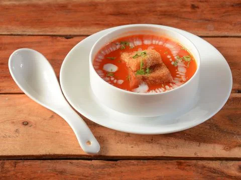 Tomato soup served over a rustic wooden background, selective focus Stock Photos