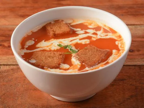 Tomato soup served over a rustic wooden background, selective focus Stock Photos