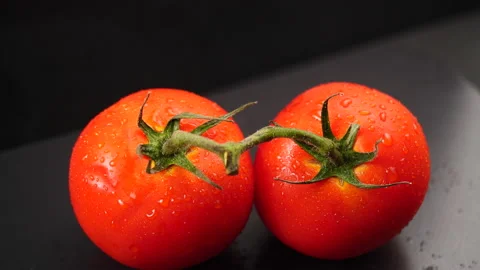 Tomato with water drops on black table. Shot by panning the camera Stock Footage 133975014