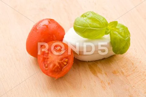 Tomatoe and mozzarella on cutting board Stock Photos