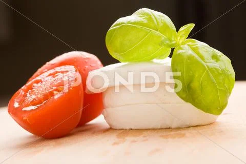 Tomatoe and mozzarella on cutting board Stock Photos