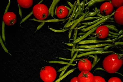 Tomatoes and asparagus on a black surface Stock Photos