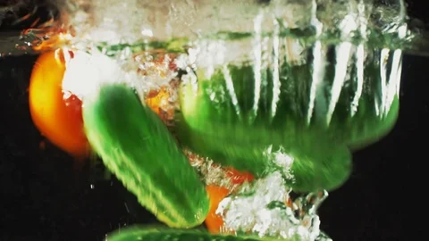 Tomatoes and cucumbers falling in water Stock Footage 83210954