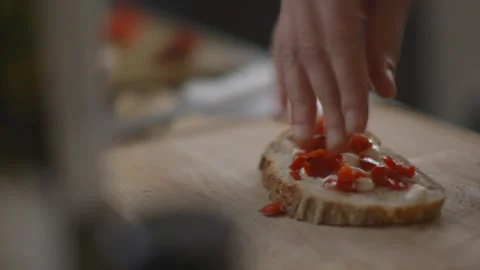 Tomatoes and pepperonis being put onto slice of bread on wooden surface Stock Footage 194478375