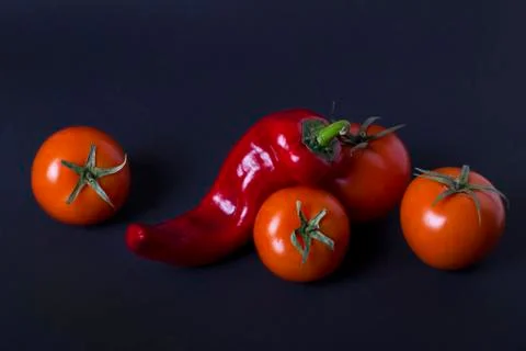 Tomatoes and red pepper on a dark background. Composition of red peppers and Foto stock