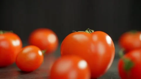 Tomatoes are spread out on the table and more are rolling into the frame. Stock Footage 269370903