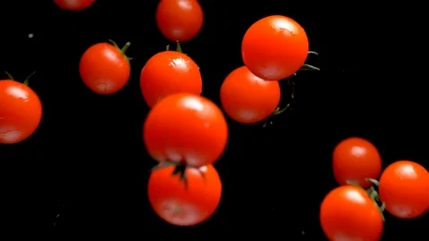Tomatoes on a black background approach the lens. Slow motion Stock Footage 104630867