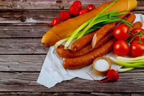 Tomatoes, bread and kielbasa with chives on wooden background. Stock Photos