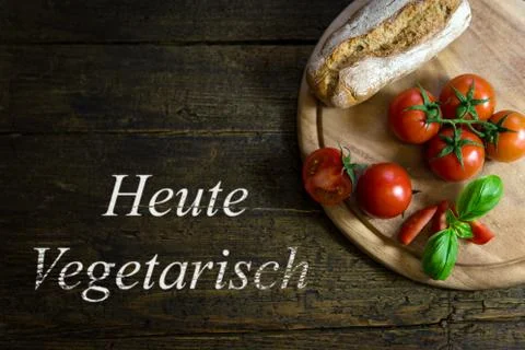 Tomatoes with bread on wooden table, text Heute Vegetarisch 스톡 사진