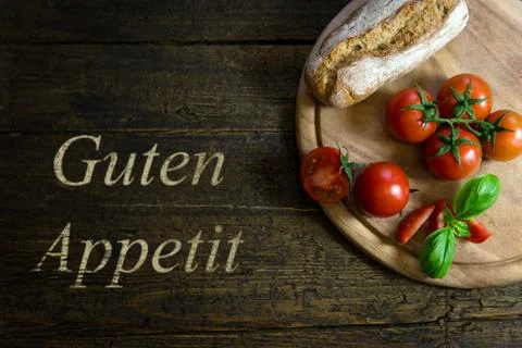 Tomatoes with bread on wooden table, text Guten Appetit Fotos Stock