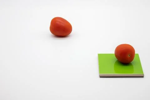 Tomatoes on colored coasters and white background Stock Photos