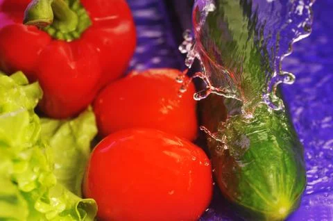 Tomatoes, cucumber and splashes Stock Photos