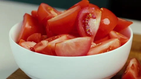 Tomatoes cut into large chunks, the cook piles them on a white plate Stock Footage 247789006
