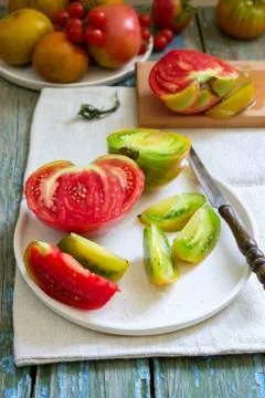 Tomatoes of different sizes and different colors and tomato slices with salt  Foto stock