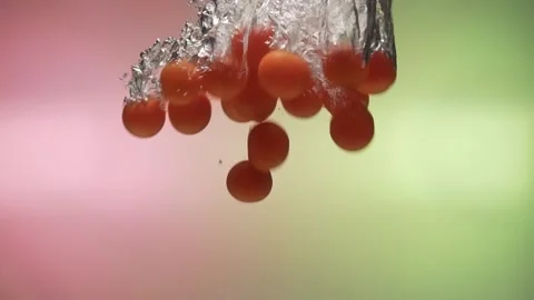 Tomatoes fall into water in slow motion. on a colored background Stock Footage 131037454