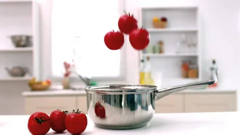 Tomatoes falling into pot in kitchen Stock Footage 213383779