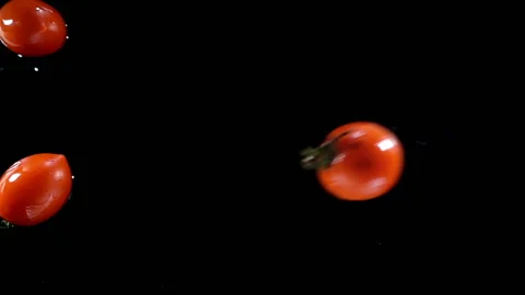 Tomatoes falling on wet black in slow motion Stock Footage 137786414