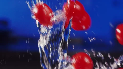 Tomatoes fly through flowing water on a blue background Vídeo Stock 159057856