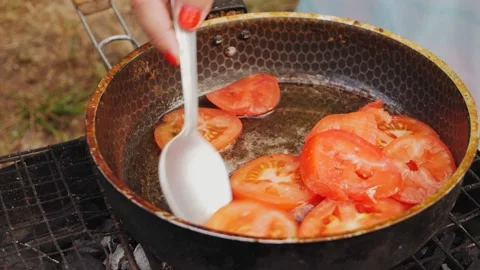 Tomatoes fried in a frying pan standing on the grass on the grill in oil are mix 库存影片 203238126