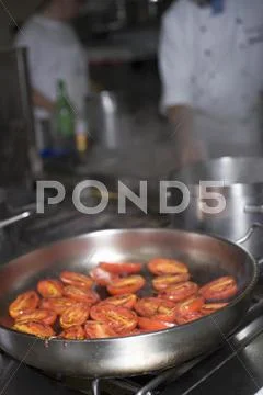 Tomatoes In Frying Pan On Stove, Chefs In Background